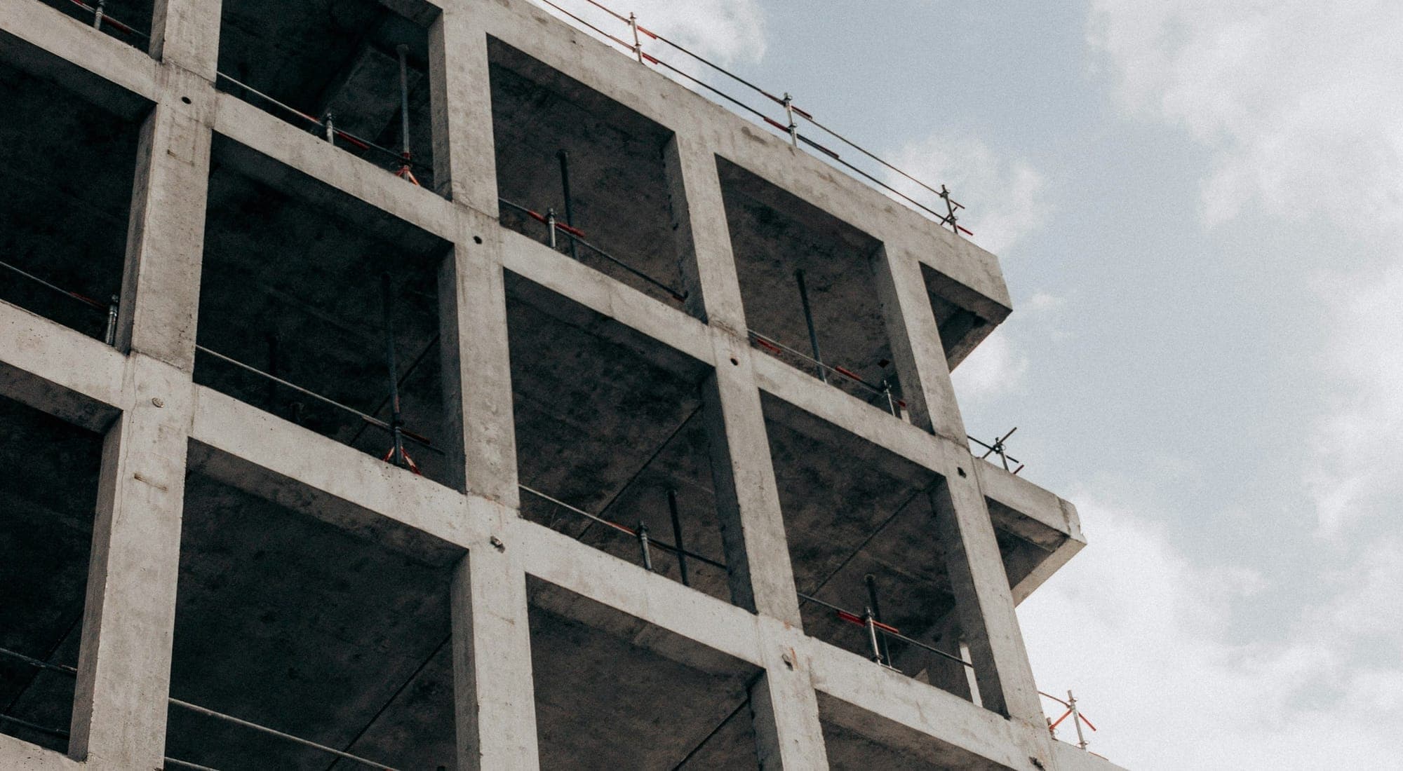 The bare concrete frame of a building under construction against an overcast sky