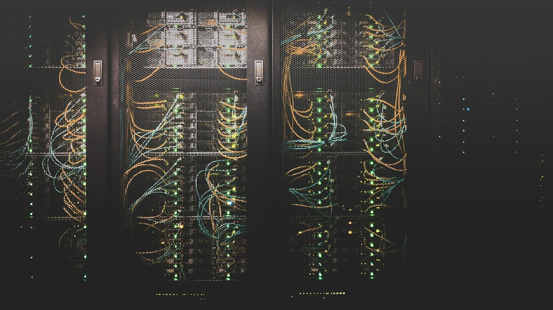Rows of cabled server cabinets in a data hall, status indicators lit